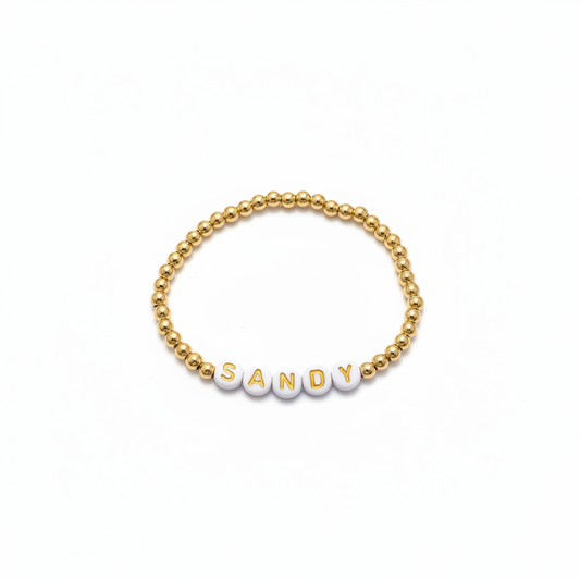 Gold beaded bracelet with personalized letter beads on white background